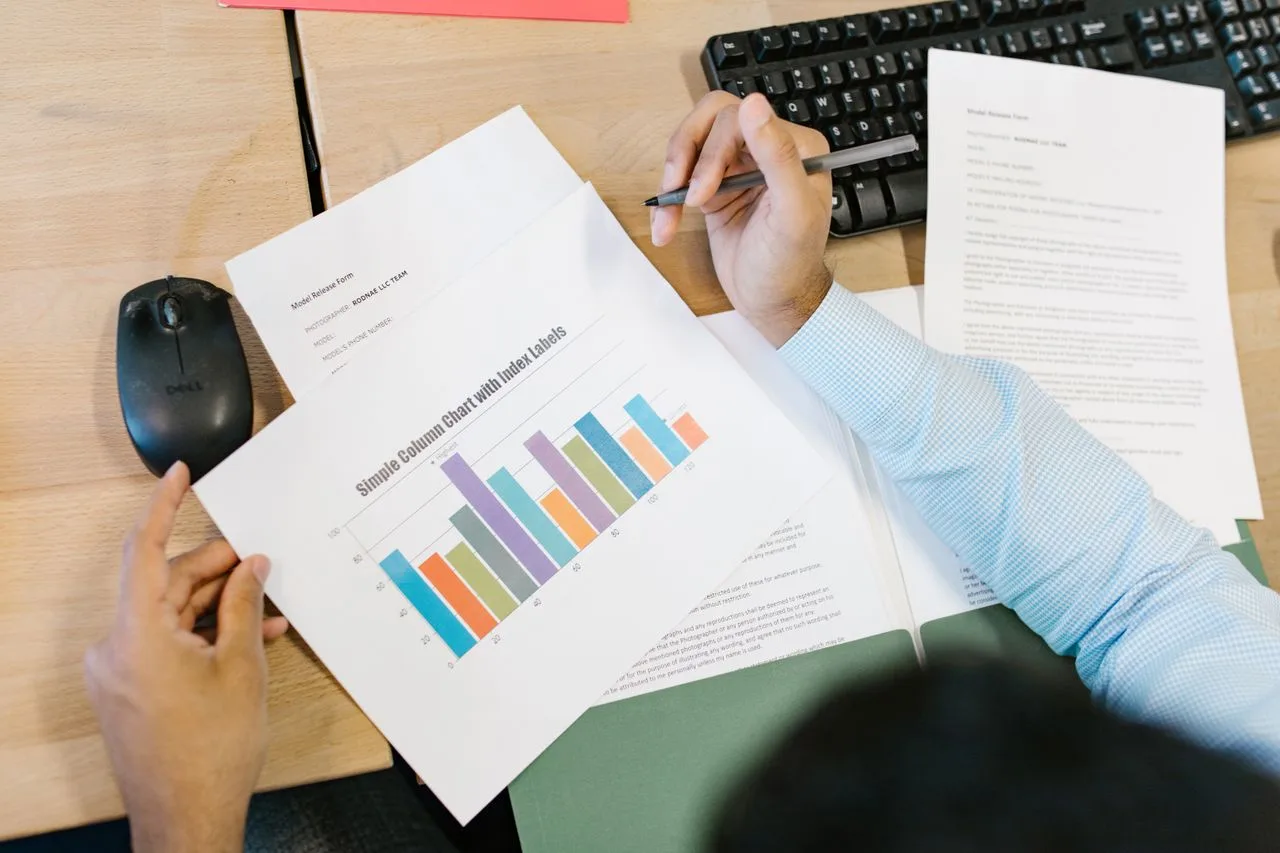 A person reviewing a printed bar chart and taking notes