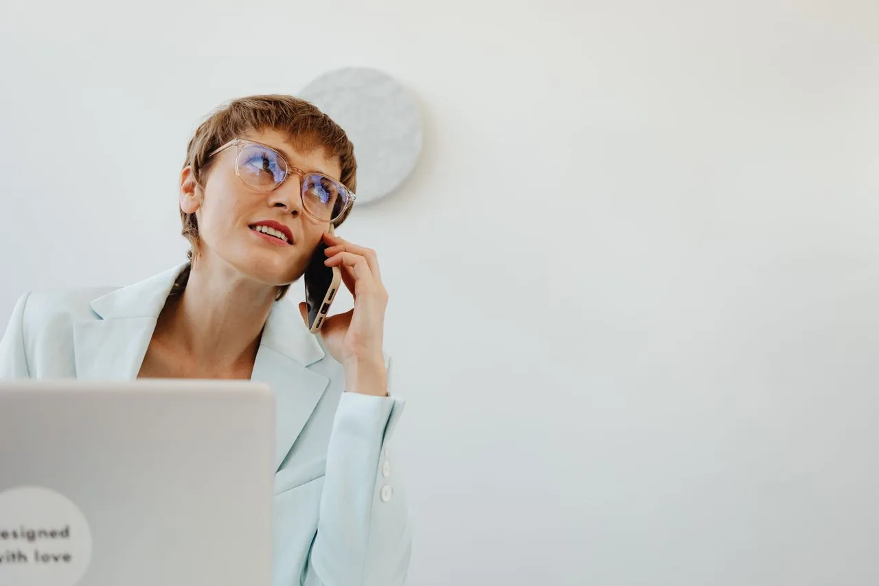 A professional speaking on a phone beside her laptop